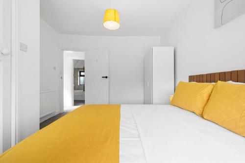 a white bedroom with a large bed with yellow pillows at 52 Furnival Road, Manchester in Manchester