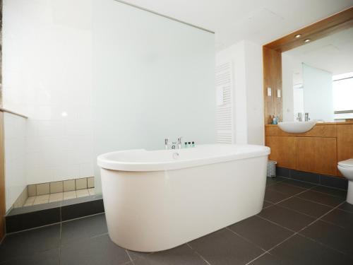 a white bathroom with a tub and a sink at BS2 Lofts Apartment by N And N Stays Ltd, Great location Close to Cabot Circus, Centre and Hospital, perfect for workers, NHS and Contractors, Private Parking Avaialable in Bristol