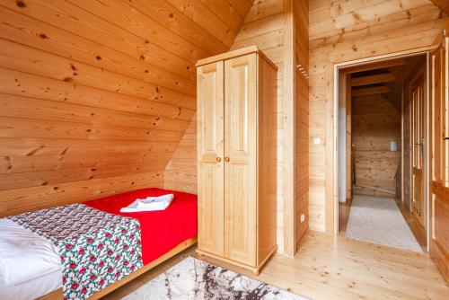 a small bedroom with a bed in a wooden room at DOMKI TATRY z jacuzzi i sauną w cenie - spokojna okolica - świetna dla rodzin z dziećmi lub grupy znajomych! in Szaflary