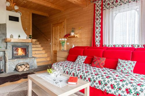 a red couch in a room with a fireplace at DOMKI TATRY z jacuzzi i sauną w cenie - spokojna okolica - świetna dla rodzin z dziećmi lub grupy znajomych! in Szaflary