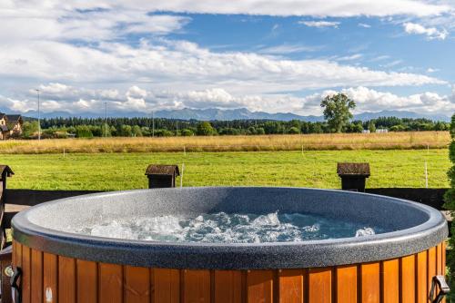 a large hot tub with water in a field at DOMKI TATRY z jacuzzi i sauną w cenie - spokojna okolica - świetna dla rodzin z dziećmi lub grupy znajomych! in Szaflary
