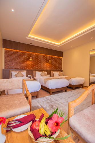a hotel room with four beds and a table with a bowl of fruit at Temple Himalaya Hotel & Spa in Pokhara
