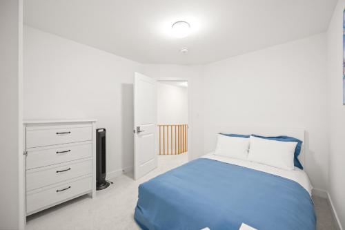 a white bedroom with a blue bed and a dresser at CEDAR Double Room with attached private Bathroom and Balcony in Toronto, ON, Canada in Toronto