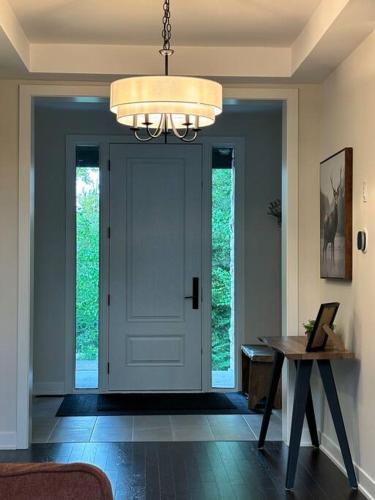 a room with a door and a table and a chandelier at Whispering Pines Muskoka 3BR 3 Ensuite Baths in Dwight