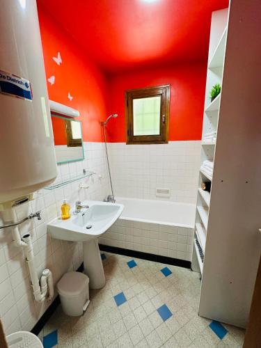 La salle de bains est pourvue de murs rouges, d'un lavabo et d'une baignoire. dans l'établissement Appart 4 pers Grande terrasse vue sur montagne, à Saint-Jean-de-Maurienne