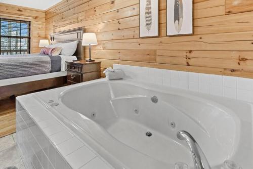 a white bath tub in a bedroom with a bed at Pitch Perfect in Sevierville