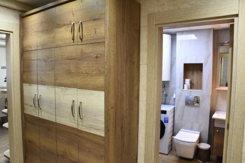 a bathroom with a wooden cabinet and a toilet at MB Apartmani Kopaonik in Kopaonik