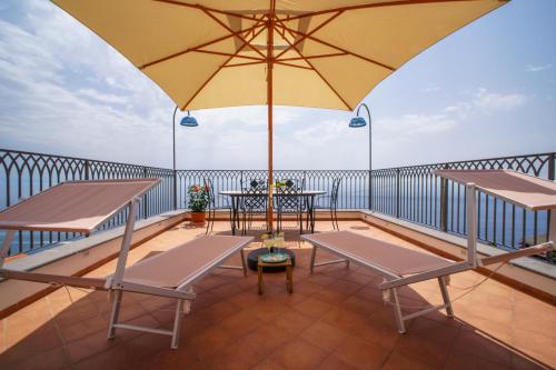a balcony with tables and a yellow umbrella at Amalfi House Marlidia in Conca dei Marini