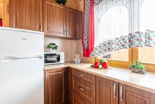 a kitchen with wooden cabinets and a white refrigerator at DOMKI TATRY z jacuzzi i sauną w cenie - spokojna okolica - świetna dla rodzin z dziećmi lub grupy znajomych! in Szaflary