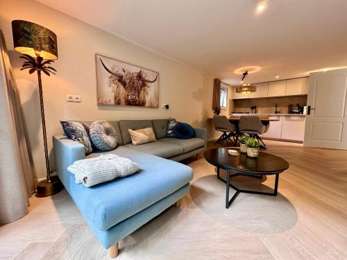 a living room with a blue couch and a table at Holiday Home Maridu Family Wellness in Hattemerbroek