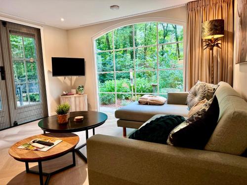 a living room with a couch and a large window at Holiday Home Maridu Family Wellness in Hattemerbroek