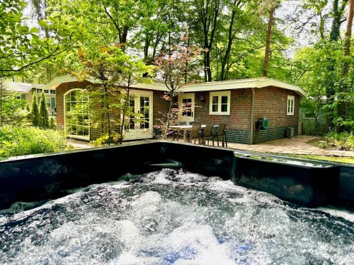 a home with a pond in front of a house at Holiday Home Maridu Family Wellness in Hattemerbroek