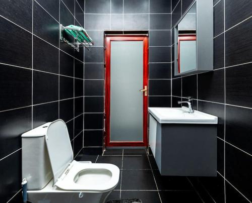 a bathroom with a toilet and a sink and a red door at Stay with Peace on Spintex road in Baatsona