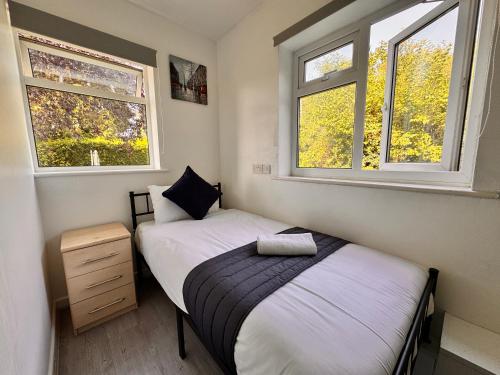 two beds in a small room with two windows at High Trees Guest House Gatwick in Horley