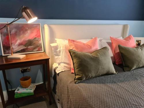 a bed with pillows and a table with a lamp at Beach Hideaway in Shanklin