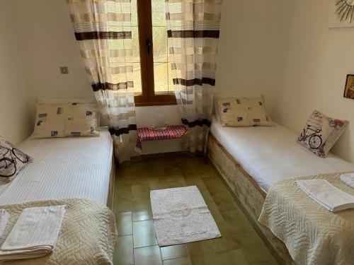 two twin beds in a room with a window at Papadiokampos Maissonete in Roússa Límni