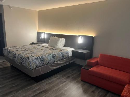 a hotel room with a bed and a red couch at Motel 6 Tulsa, OK Airport in Tulsa