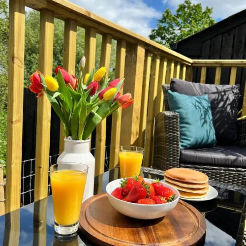 a table with a bowl of strawberries and a vase of flowers at Mourne Magic House-Riverside luxury in Newcastle in Newcastle