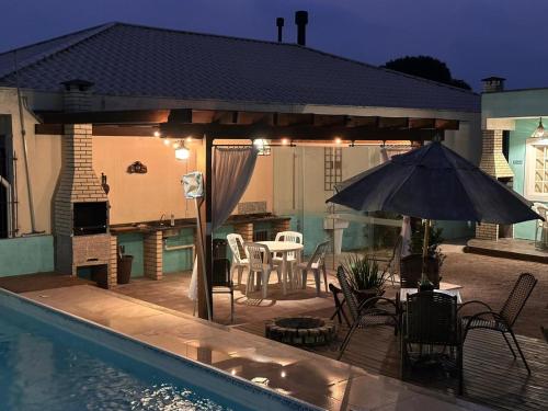 a patio with an umbrella next to a swimming pool at 01 - Casa Praia da Pinheira in Palhoça