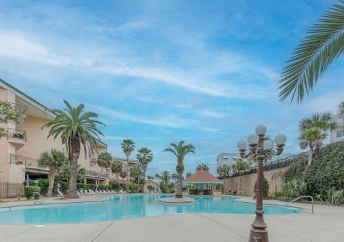 a pool at a resort with palm trees and a street light at Ocean View Luxury Steps to Beach in Galveston