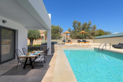 un patio con tavolo e sedie accanto alla piscina di Villa Lambis Harmonia a Líndos