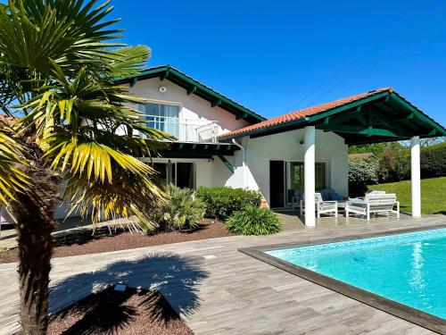 une maison avec un palmier et une piscine dans l'établissement Villa à 5min de Bayonne avec Piscine chauffé et salle de sport, à Saint-Pierre-dʼIrube