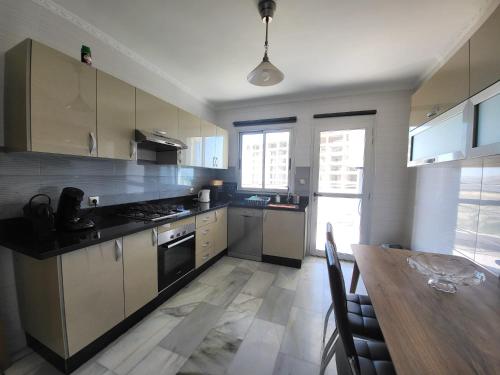 Mont Blanc :Appartement, vue sur mer à 2 minutes de la gare. في طنجة: مطبخ مع طاولة خشبية وغرفة طعام