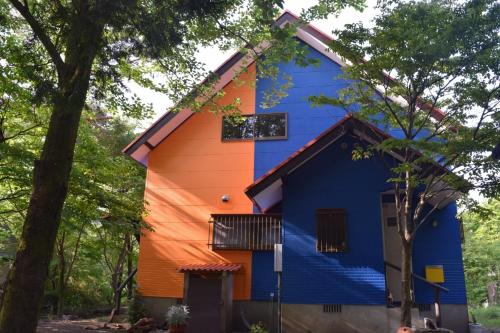 a blue and orange house in the woods at Aso Dream Villa - Vacation STAY 17297 in Okurabaru