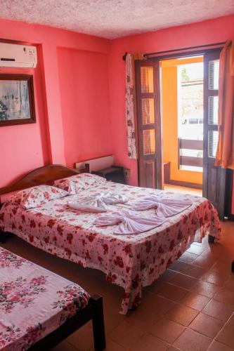 a bedroom with a bed with a red wall at Pousa Hotel Sonho de Verão in Vera Cruz de Itaparica