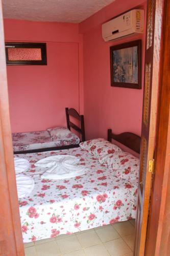 two beds in a room with pink walls at Pousa Hotel Sonho de Verão in Vera Cruz de Itaparica