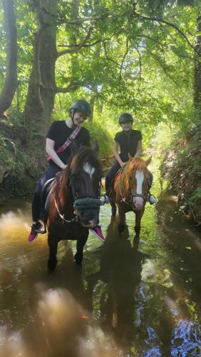 2 personnes voyageant à cheval à travers un ruisseau dans l'établissement La cabane aux chevaux, à Varages
