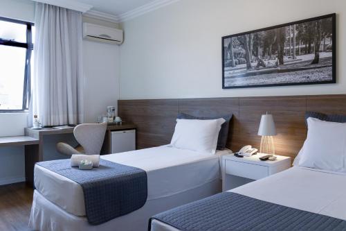 a hotel room with two beds and a chair at Caitá Hotéis in Concordia