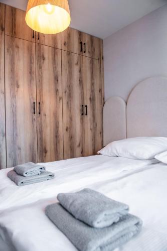 a bedroom with a white bed with towels on it at Apartamenty Balijskie in Gliwice