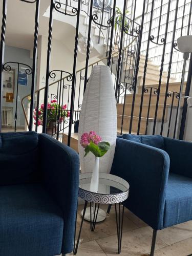 a vase with flowers on a table next to two blue chairs at Hotel Markgraf in Bad Bellingen