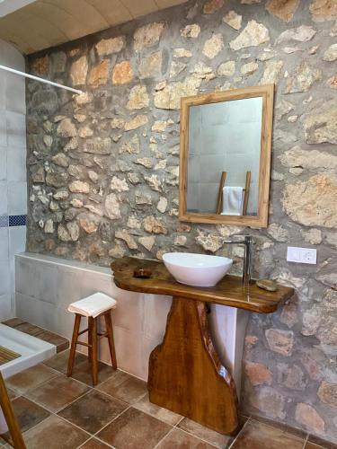 a bathroom with a sink and a mirror on a stone wall at La Cueva de Miravet - villa de lujo en la cima de la montaña con vistas al mar in Cabanes