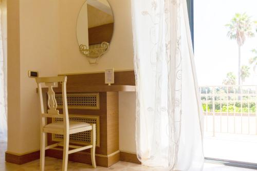 a mirror and a chair in a room with a table at Villa Rosa Antico Dimora Storica in Otranto