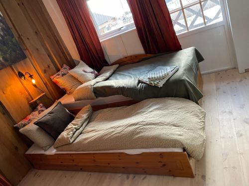 a room with two beds with pillows and a window at Hyggelig og velutstyrt leilighet i Lom sentrum in Lom