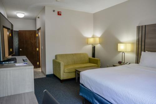 a hotel room with a bed and a chair at Baymont by Wyndham O'Fallon St. Louis Area in O'Fallon