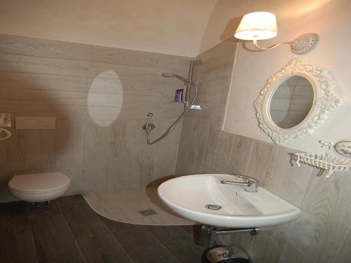 Un baño con lavabo, inodoro y espejo. en Domus Alba, en Martina Franca