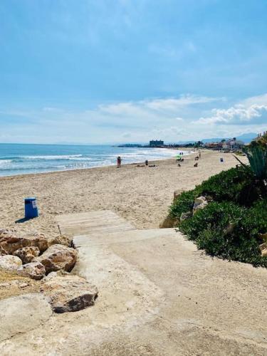 a sandy beach with people walking on the beach at El Riuet-Chalet apartamento a 1 minuto de la playa, Cullera in Cullera
