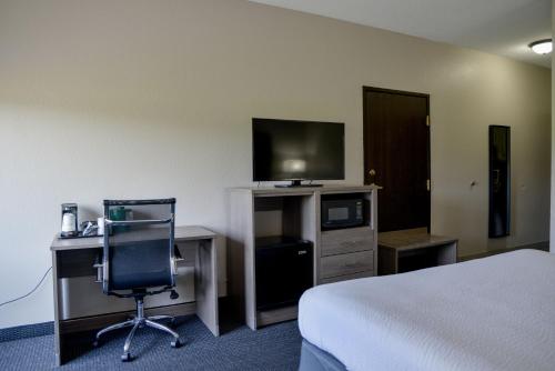a hotel room with a bed and a desk and a television at Baymont by Wyndham O'Fallon St. Louis Area in O'Fallon