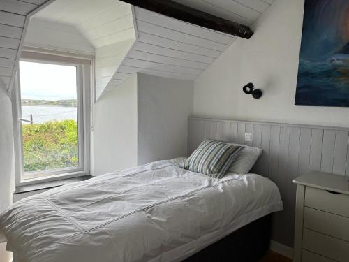 a white bedroom with a bed and a window at Pier Cottage with private water access to Colla Pier in Schull