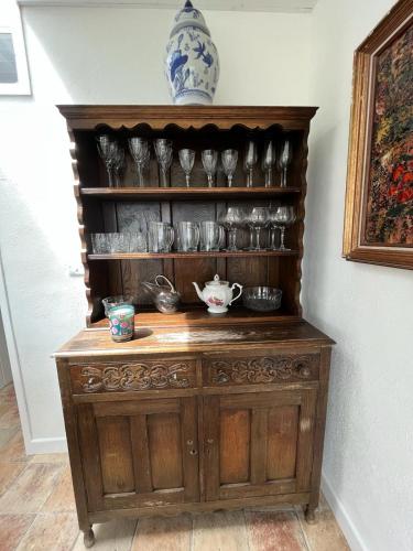 a wooden cabinet with cups and dishes on it at Pier Cottage with private water access to Colla Pier in Schull