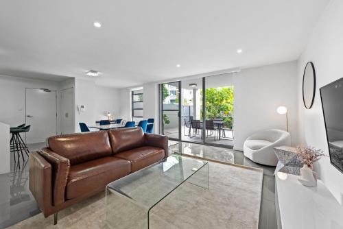 a living room with a leather couch and a glass table at Cirque Boutique Apartments - Hosted by Coastal Letting Co. in Brisbane