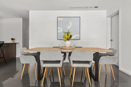 a dining room table with chairs and a vase with flowers at Cirque Boutique Apartments - Hosted by Coastal Letting Co. in Brisbane