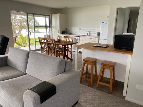 a living room with a couch and a kitchen at Athenree Beach House in Athenree