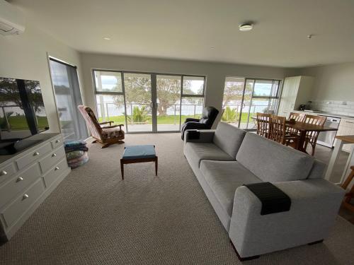 a living room with a couch and a tv at Athenree Beach House in Athenree