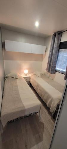 deux lits dans une petite pièce avec une fenêtre dans l'établissement MOBILE-HOME au COEUR des LANDES, à Herm