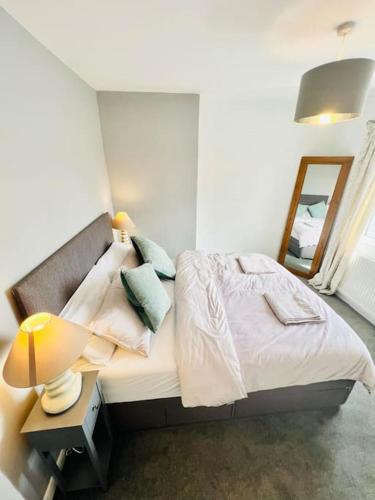 a bedroom with a bed with a lamp and a mirror at Tor View Flat in Street
