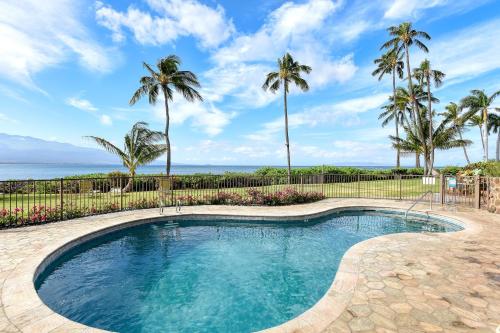 a swimming pool with palm trees and the ocean at Maalaea Banyans 214 in Wailuku